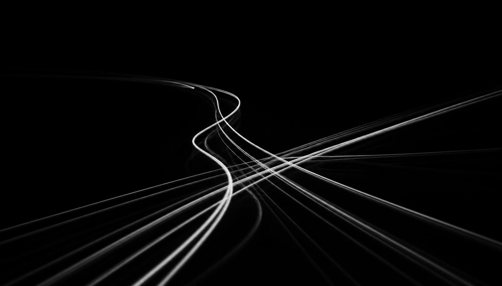 Long-exposure white light trails crossing on a black background, representing message paths between systems
