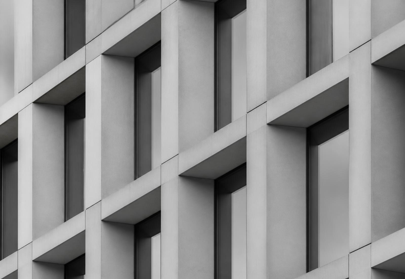 Black and white photograph of a modular concrete and glass building facade forming a repeating grid